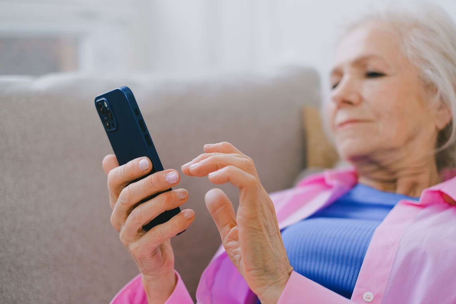 Check-in calls for seniors — an older adult at home answers a friendly phone check-in on a smartphone