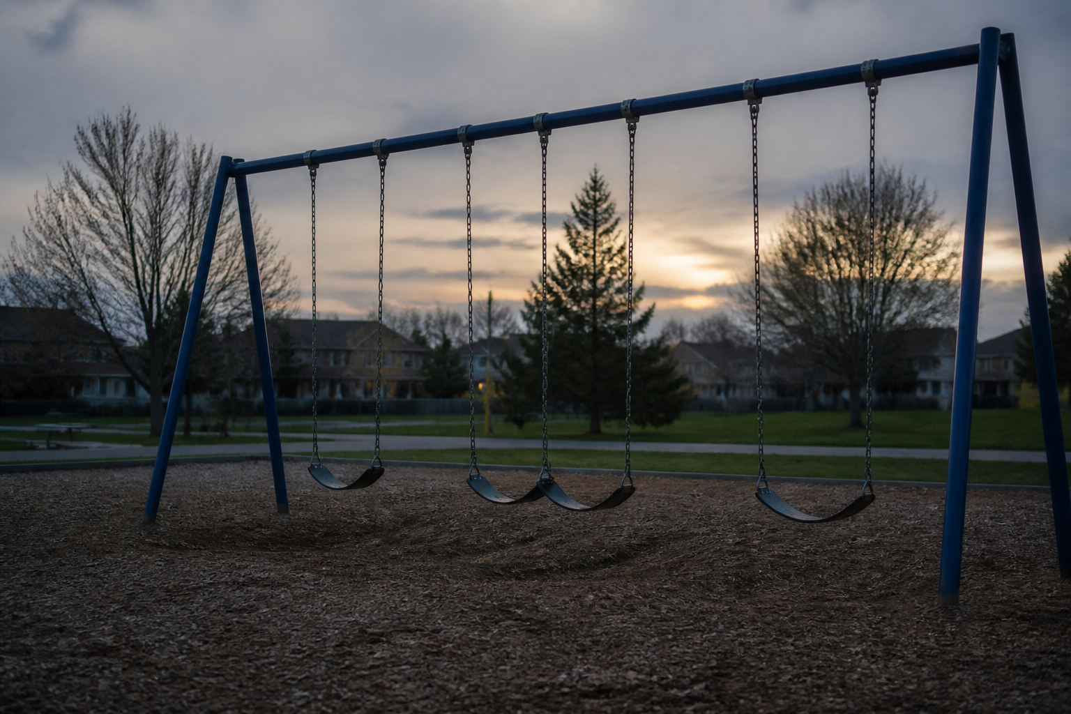 social isolation in childhood — an empty playground swing at dusk, no children present