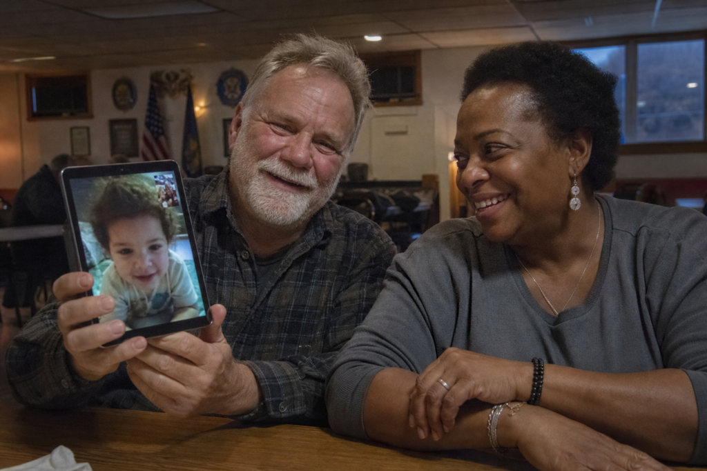 virtual companion for elderly — a man and woman sharing a video call together at a VFW hall table